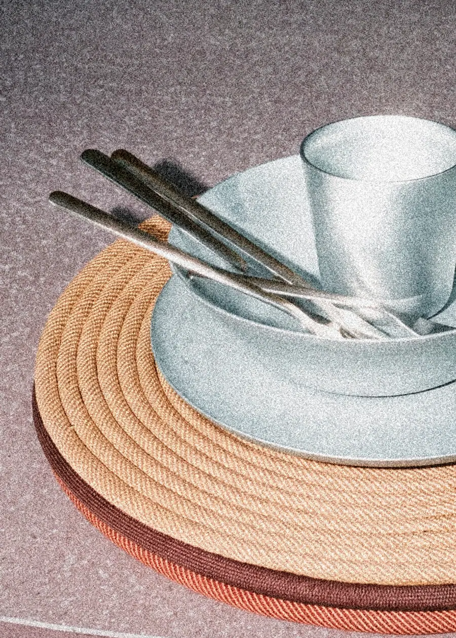 Platos, taza y cubiertos de Argo apilados sobre el mantel de cuerda