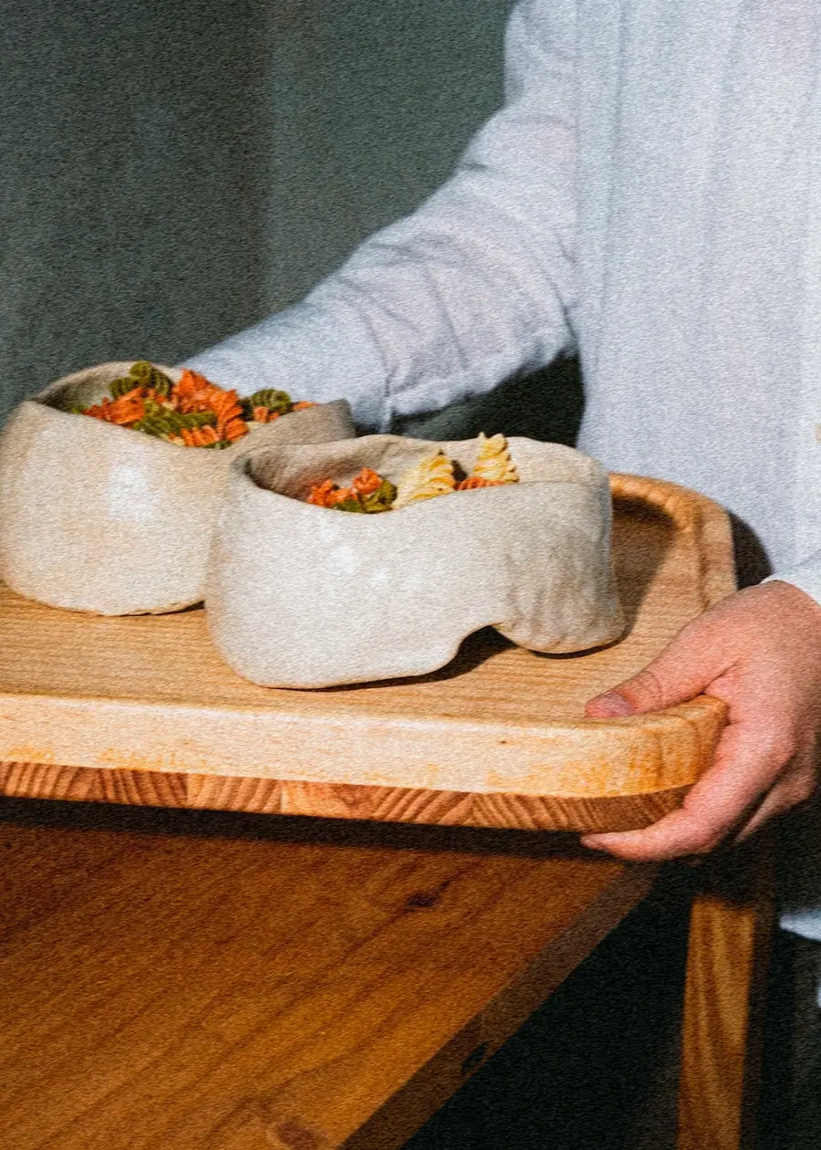 Una mano sostiene la bandeja de Earl con dos cuencos Ware